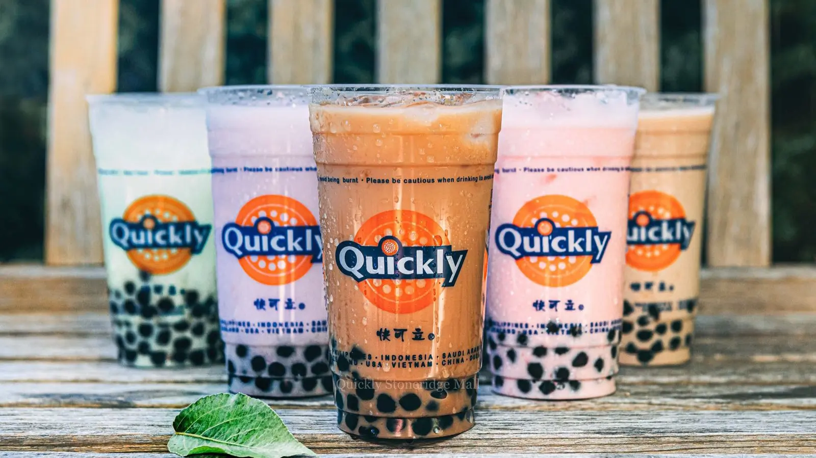 Variety of bubble teas with tapioca pearls on a wooden bench at Quickly Stoneridge Mall, a Fast Food Restaurant in Pleasanton