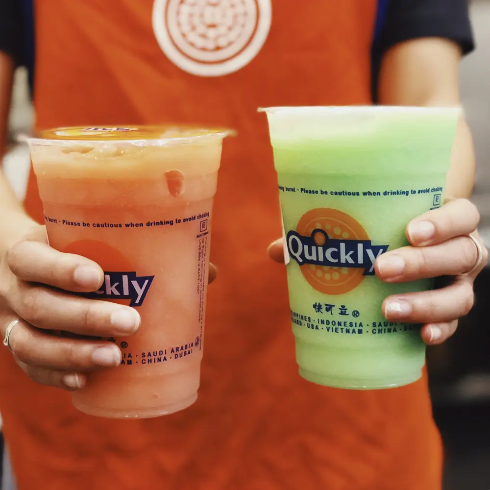 Two fruity slushes, pink and green, held by a staff at Quickly Stoneridge Mall, a Fast Food Restaurant in Pleasanton
